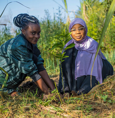 Two young women plant a tree at G-BIACK